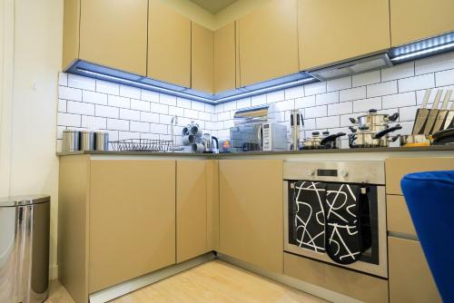 una pequeña cocina con armarios amarillos y lavavajillas en Classy Modern Flat: Free Parking, Gym & Roof Garden en Stevenage