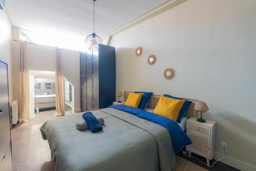1 dormitorio con 1 cama grande con almohadas azules y amarillas en Appartement Duplex, en Le Thillay