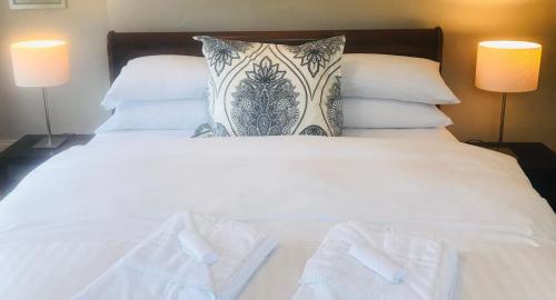 a bedroom with a white bed with two lamps at Grey Heron Townhouse in Newcastle