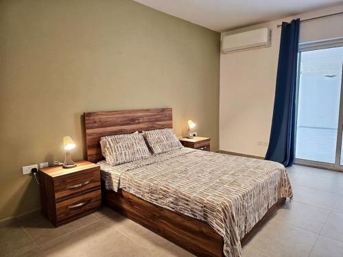 a bedroom with a bed and two lamps on night stands at Sleeps 6 Spacious Apartment St Pauls Bay in St. Paul's Bay