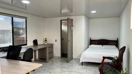 Schlafzimmer mit einem Bett, einem Schreibtisch und Stühlen in der Unterkunft Mirador Alacala in Envigado