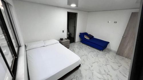 ein Schlafzimmer mit einem weißen Bett und einem blauen Sofa in der Unterkunft Mirador Alacala in Envigado