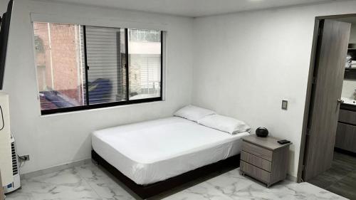 ein weißes Schlafzimmer mit einem Bett und einem Fenster in der Unterkunft Mirador Alacala in Envigado