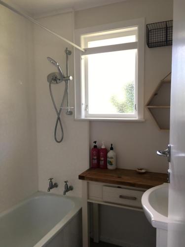baño con bañera, lavabo y ventana en Costal Canvas opononi en Opononi