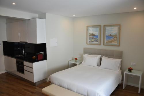 a bedroom with a white bed and a flat screen tv at Vicente´s LOB ( Lobos Ocean Breeze) in Câmara de Lobos
