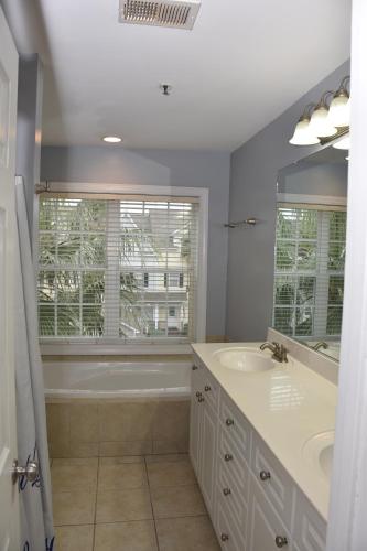 Large Private Room with Balcony and bathroom في تشارلستون: حمام به مغسلتين وحوض استحمام ونافذة