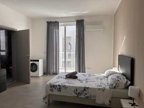 um quarto com uma cama e uma grande janela em Qawra penthouse 4person AC+wifi em St. Paul's Bay