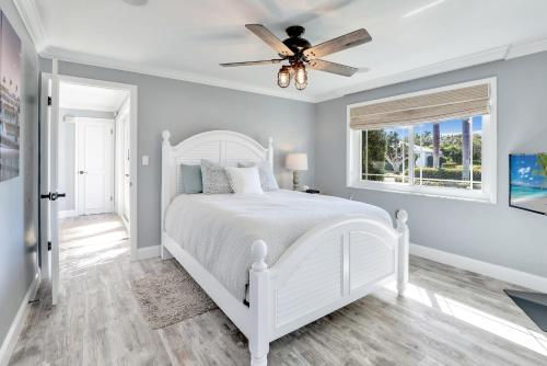 a white bedroom with a white bed and a ceiling fan at Family Friendly Fort Myers Vacation Rental with Pool in Fort Myers