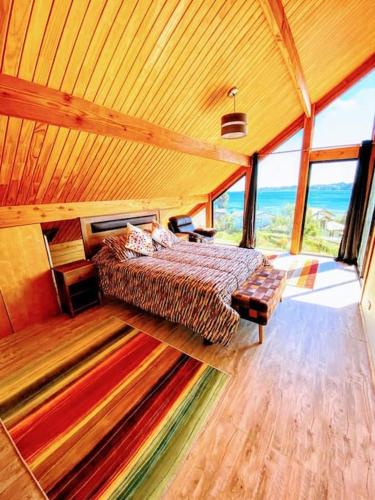 a bedroom with a bed in a room with windows at Espectacular casa Playa Hermosa, lagos y volcanes in Llanquihue