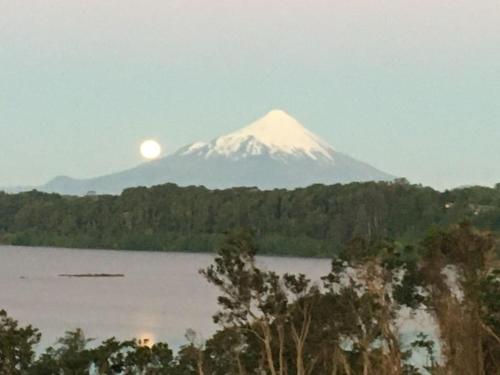 a snow covered mountain with the moon in the background at Espectacular casa Playa Hermosa, lagos y volcanes in Llanquihue