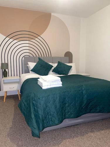 a bedroom with a bed with a green comforter at Modern 2 Bed in the heart of Maidstone in Kent