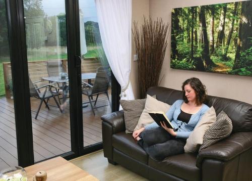 a woman sitting on a couch with a laptop at Upton Lakes Lodges in Cullompton