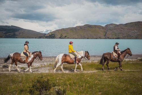 three people riding horses by a body of water at CABAÑA ESTANCIA LAZO in Torres del Paine