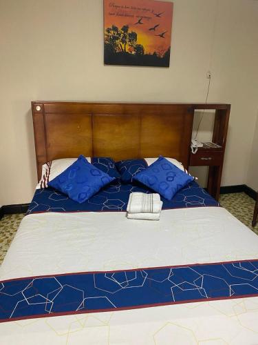 a large bed with blue pillows on top of it at Hotel La Estrella de la Mañana in Tuluá