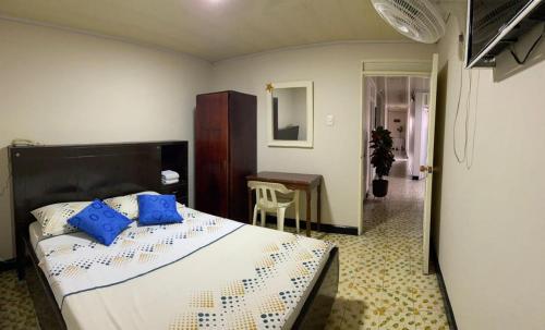 Un dormitorio con una cama con almohadas azules y una mesa. en Hotel La Estrella de la Mañana en Tuluá