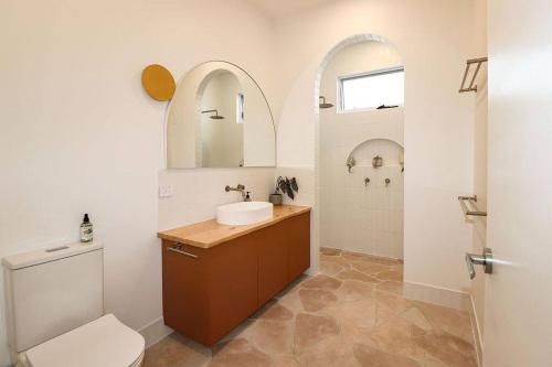 a bathroom with a sink and a toilet and a mirror at Palm Springs in Port Lincoln! in Port Lincoln