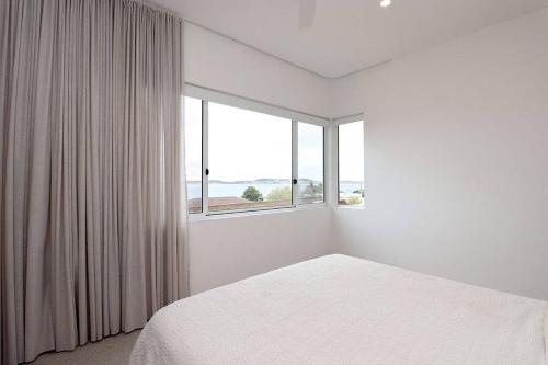 a white bedroom with a bed and a window at Palm Springs in Port Lincoln! in Port Lincoln
