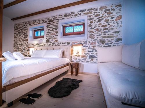 a bedroom with a stone wall and a bed and a couch at SELO Luxury Suite in Álli Meriá