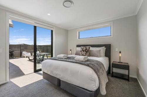 1 dormitorio con 1 cama grande y balcón en Harakeke Holiday Haven - Taupo en Taupo