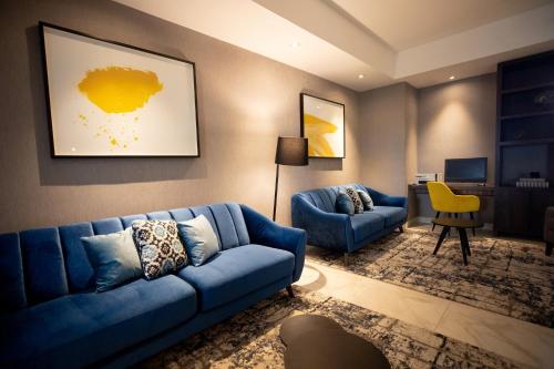 sala de estar con sofá azul y silla amarilla en voco Saltillo Suites, an IHG Hotel en Saltillo