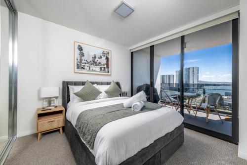 ein Schlafzimmer mit einem großen Bett und einem großen Fenster in der Unterkunft Sensational City Apartment with Lake Views - Benjamin Way ACT in Canberra
