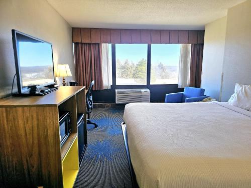 a hotel room with a bed and a flat screen tv at Days Inn by Wyndham Rolla in Rolla