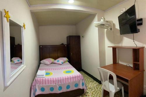 Habitación pequeña con cama y escritorio. en Hotel La Estrella de la Mañana en Tuluá