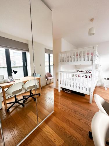 1 dormitorio con cuna blanca, mesa y silla en Drummond rooms, en Londres