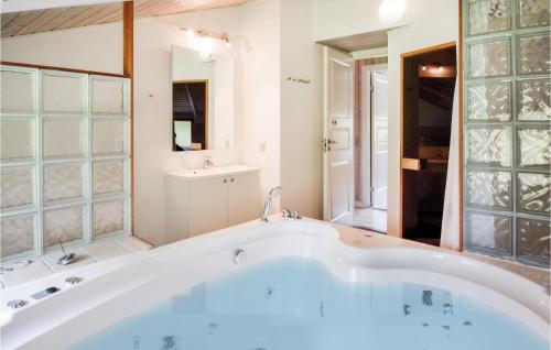 y baño con bañera grande y espejo. en 4 Bedroom Awesome Home In Tranekr, en Skattebølle