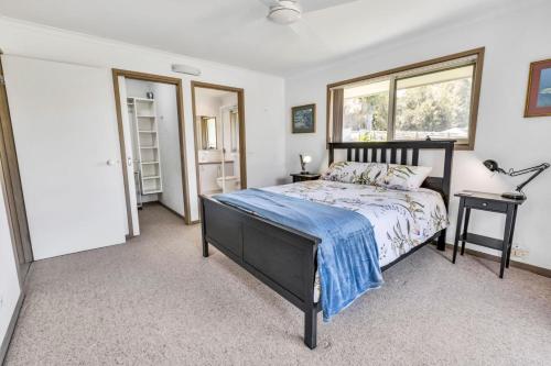 un dormitorio con una cama y una ventana en Sheerwater Jetty, en Paynesville