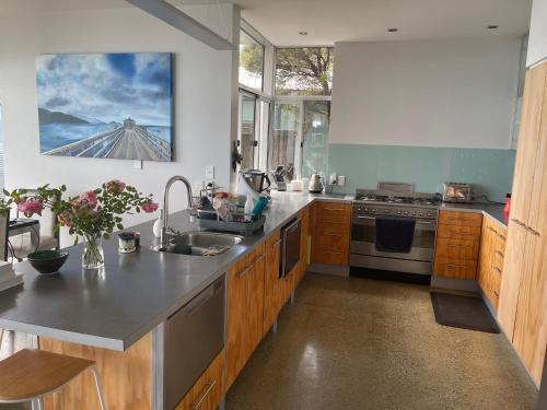 eine Küche mit Holzschränken und Küchengeräten aus Edelstahl in der Unterkunft Stunning Views over Tasman Bay in Nelson
