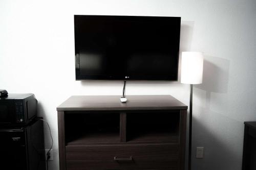a flat screen tv on top of a wooden stand with a lamp at Econo Lodge in Clarks Summit