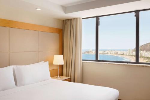 a hotel room with a bed and a large window at Hilton Copacabana Rio de Janeiro in Rio de Janeiro