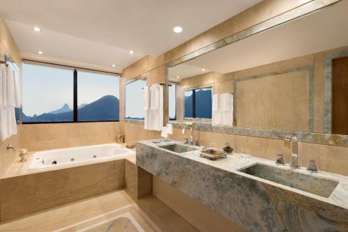 a large bathroom with a tub and a large mirror at Hilton Copacabana Rio de Janeiro in Rio de Janeiro