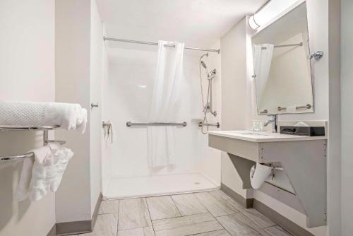 baño blanco con ducha y lavamanos en Quality Inn & Conference Center Panama City, en Panama City