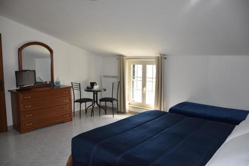ein Schlafzimmer mit einem blauen Bett und einem Tisch mit Stühlen in der Unterkunft Monte Cucco B&B in Scheggia e Pascelupo