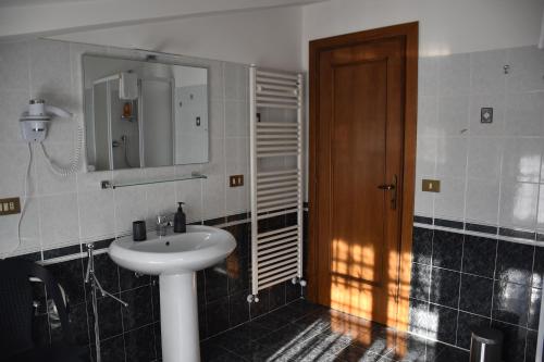 ein Badezimmer mit einem Waschbecken und einer Holztür in der Unterkunft Monte Cucco B&B in Scheggia e Pascelupo