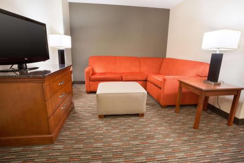 a living room with an orange couch and a tv at Drury Inn & Suites Columbus Grove City in Grove City