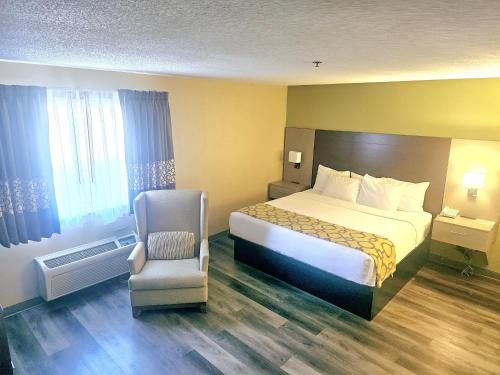 a hotel room with a bed and a chair at Baymont by Wyndham Rolla in Rolla