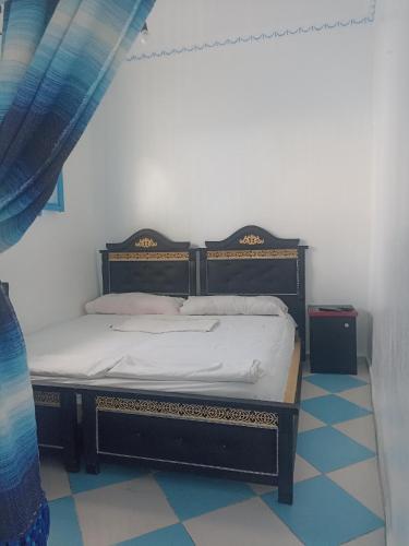 a bed in a bedroom with a blue and white floor at The little house in Chefchaouen