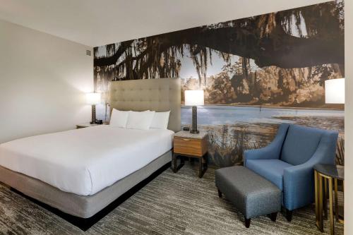 a hotel room with a bed and a blue chair at Drury Plaza Hotel Tallahassee in Tallahassee