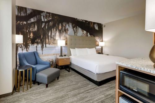 a hotel room with a bed and a blue chair at Drury Plaza Hotel Tallahassee in Tallahassee