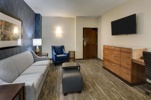 a living room with a couch and a tv at Drury Plaza Hotel Tallahassee in Tallahassee