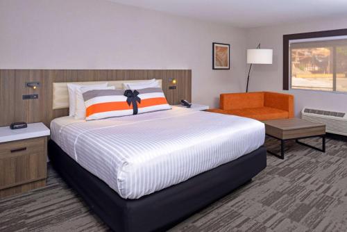a bedroom with a large bed and an orange chair at La Casa Modesto, Ascend Hotel Collection in Modesto