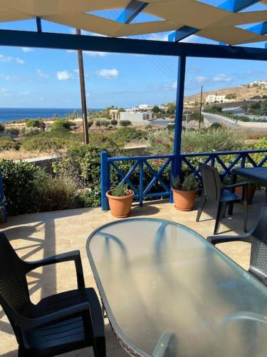 a glass table and chairs on a patio with the ocean at House by the beach,next to village,sunset view in Finikas