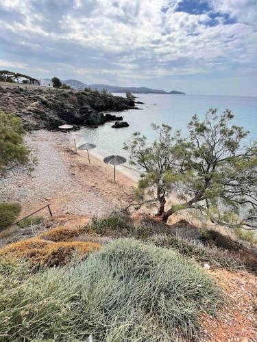 a beach with two umbrellas on the shore at House by the beach,next to village,sunset view in Finikas