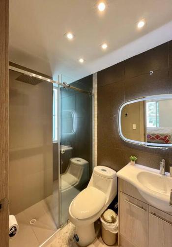 een badkamer met een toilet, een wastafel en een spiegel bij Apartamento en Resort Playa Azul in Tonsupa