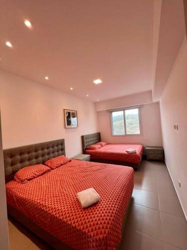 een slaapkamer met 2 bedden en rode dekbedden bij Apartamento en Resort Playa Azul in Tonsupa