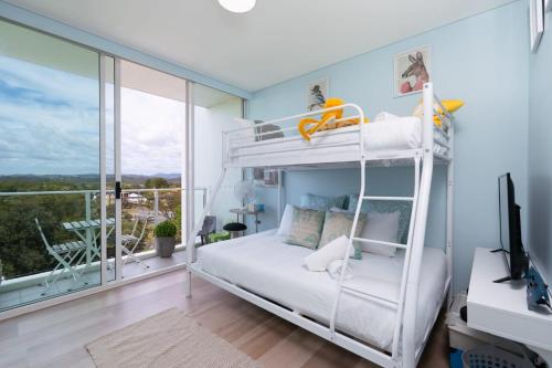 1 dormitorio con litera blanca y escritorio en Kirra Surf Apartments en Gold Coast