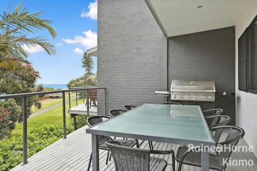 a balcony with a table and chairs and a grill at Beach House Kendalls in Kiama